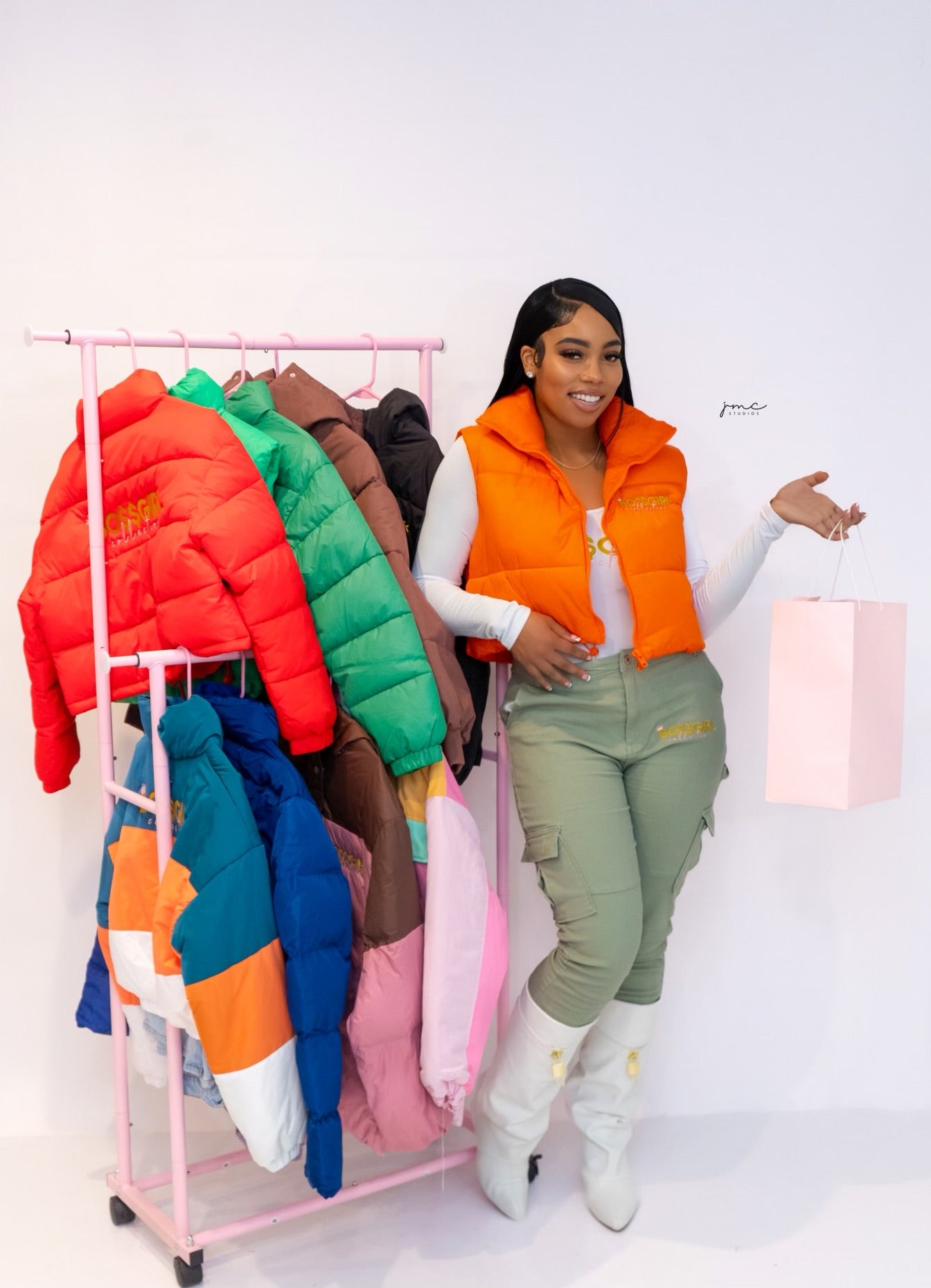 Founder standing with trendy clothing rack display puffer vest and jacket merchandise.